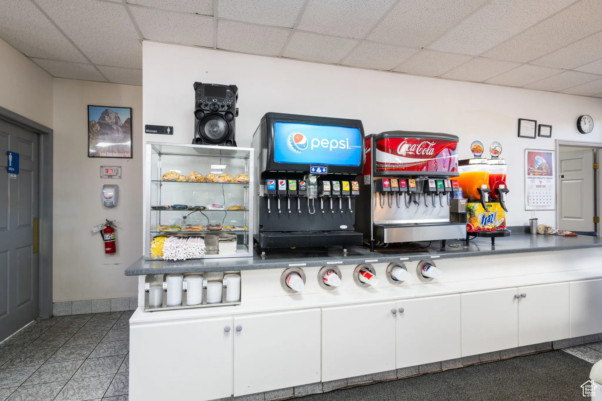 Bar area featuring dark countertops, a drop ceiling, white cabinetry, and open shelves