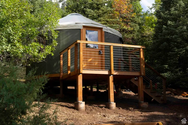 View of jungle gym with a deck, stairs, and view of wooded area