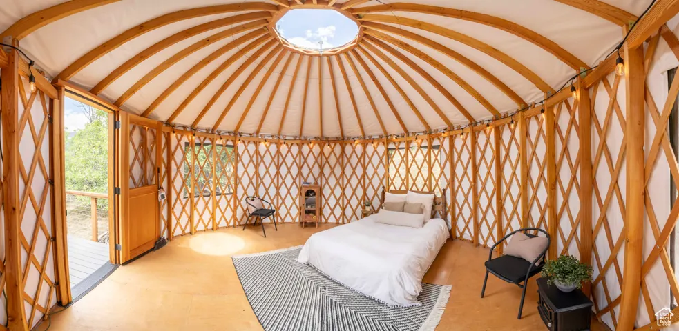Unfurnished bedroom with vaulted ceiling, a sunroom, and wood finished floors