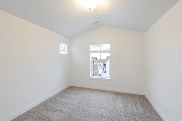 Empty room with light colored carpet and baseboards