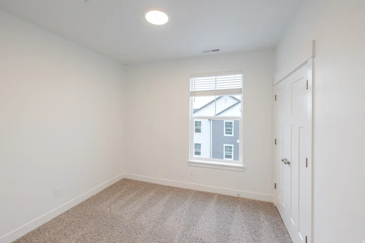 Empty room with light colored carpet and baseboards