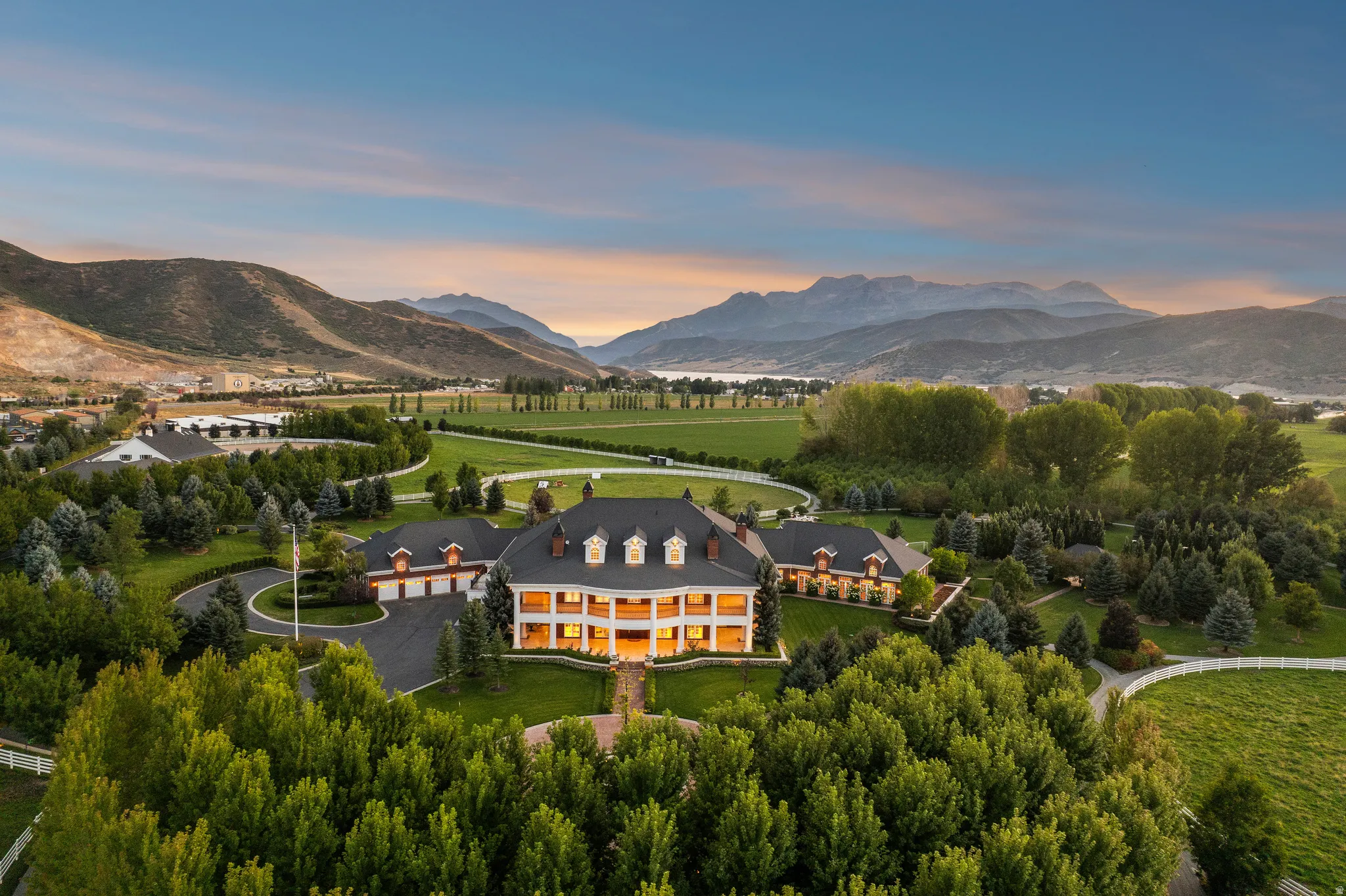 Expansive estate featuring a large main residence with a prominent front porch, multiple dormer windows, and attached garage structures