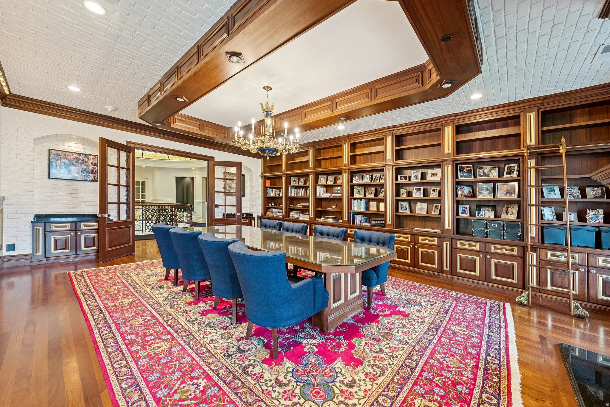 Expansive room featuring hardwood flooring, extensive built-in shelving with integrated cabinetry, a white brick-patterned ceiling, and a prominent chandelier