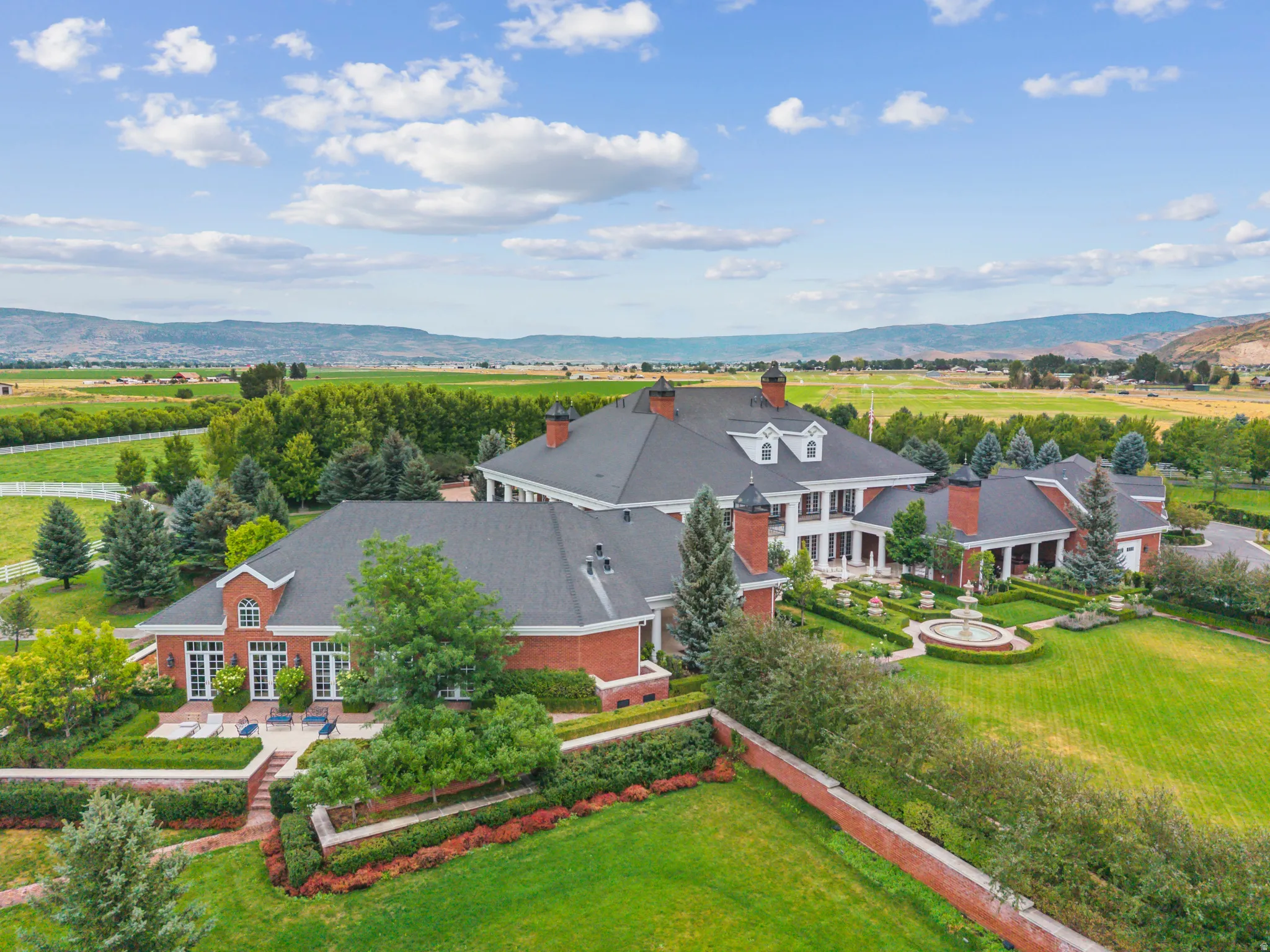 Expansive estate featuring a red brick exterior, multiple dormer windows, and a dark shingle roof