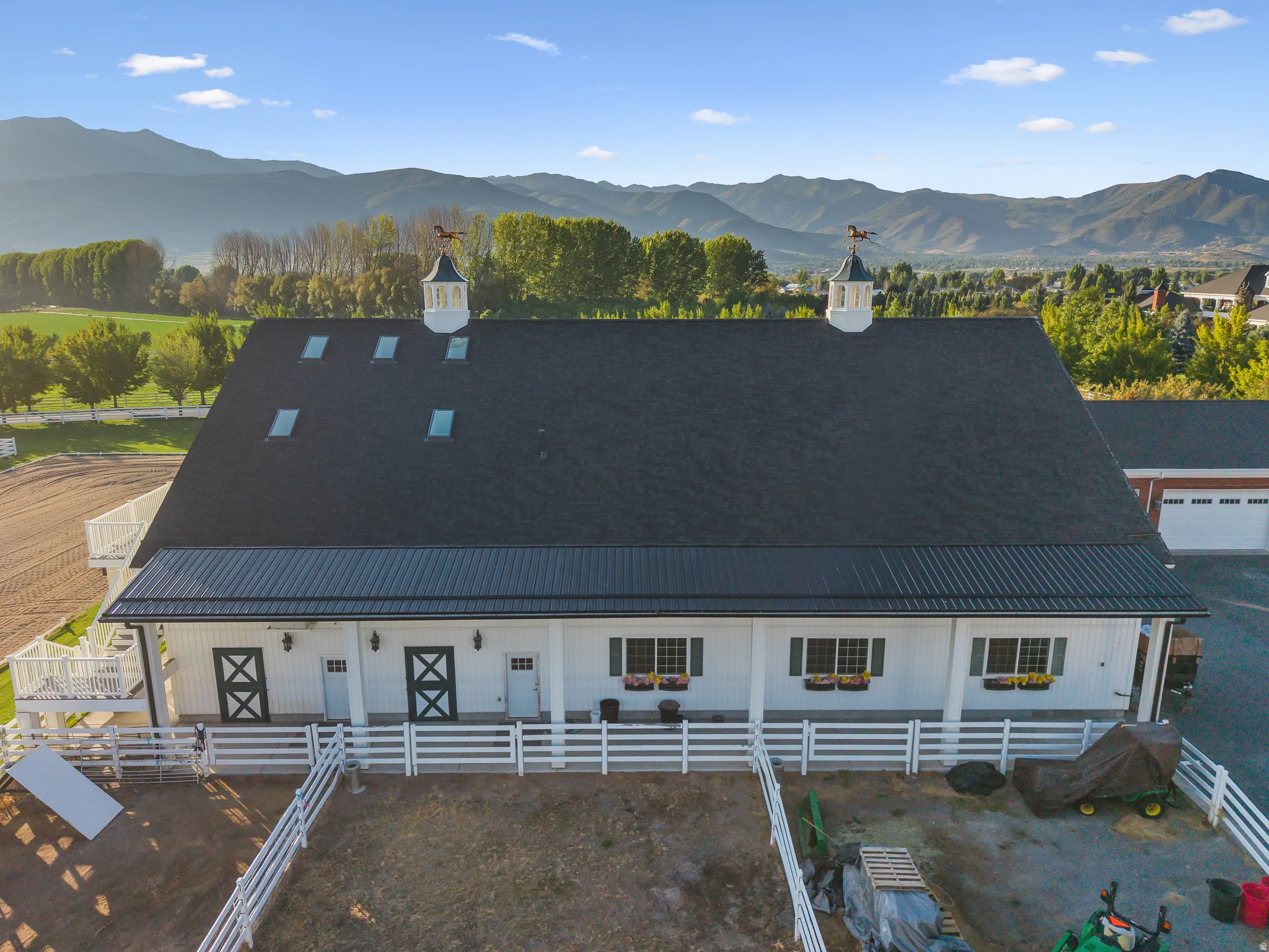 White barn structure with a dark shingle roof and metal overhang