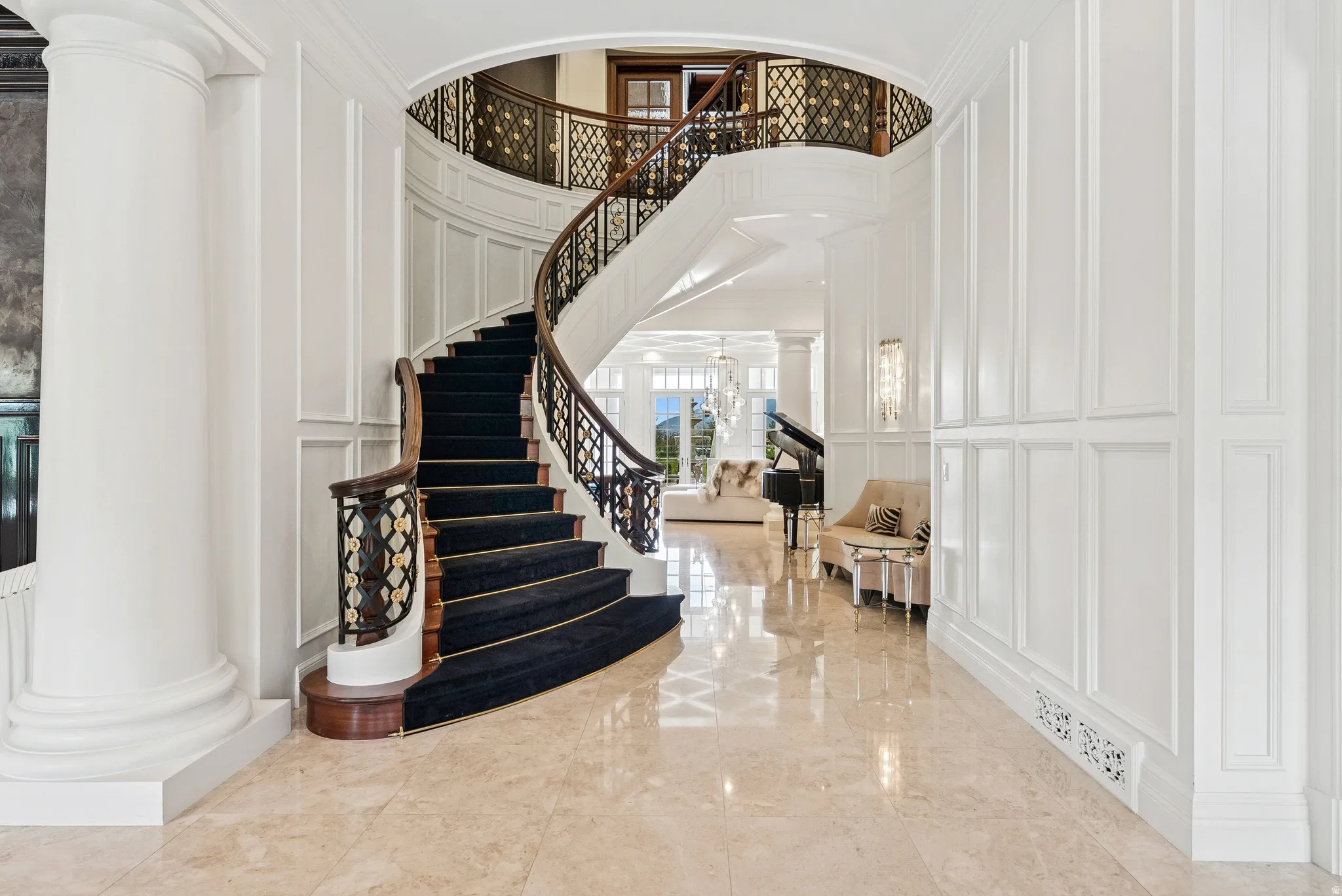 Grand entry featuring a curved staircase with dark wood handrails and ornate balusters, complemented by a black carpet runner