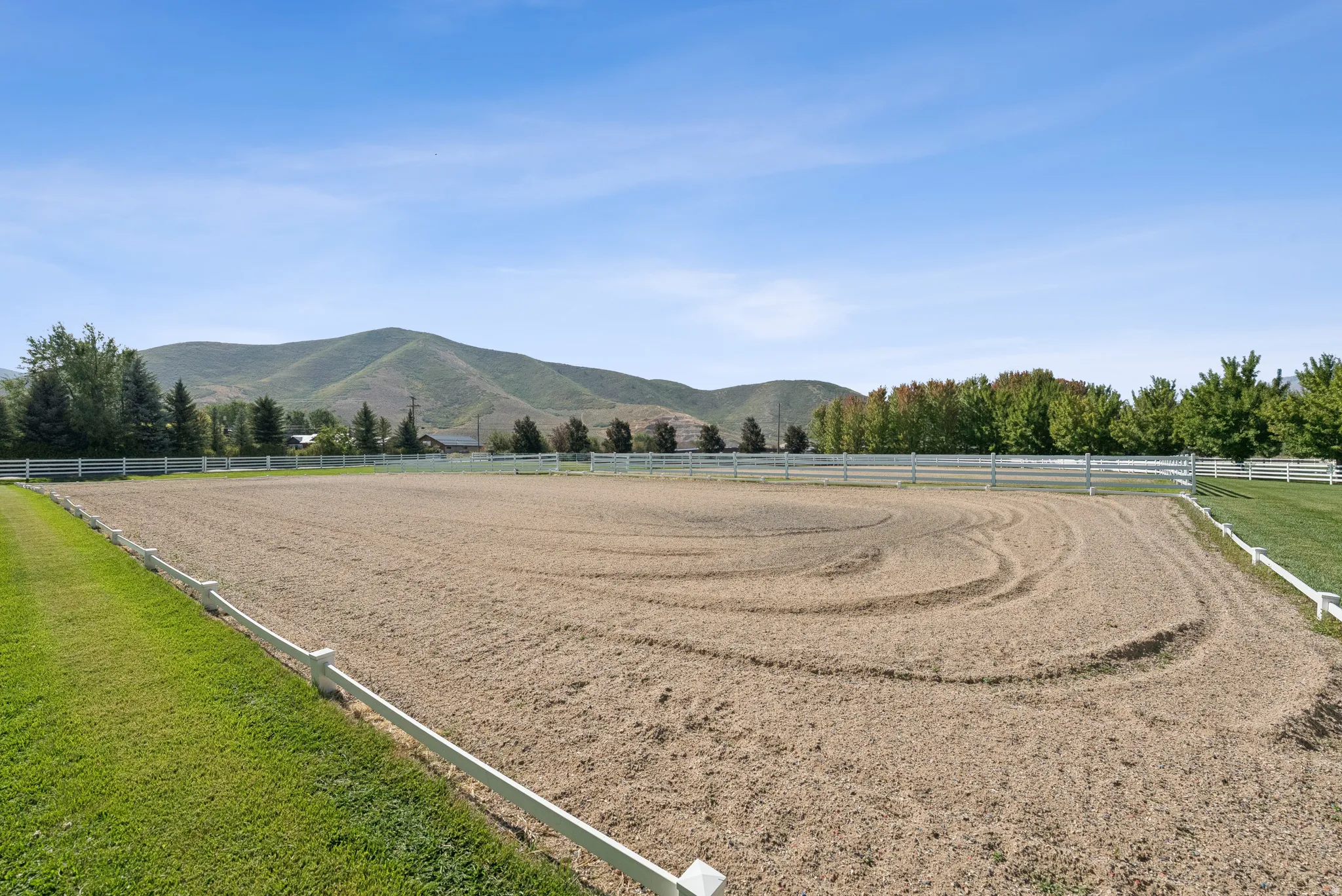Expansive outdoor arena featuring sand footing and white perimeter fencing