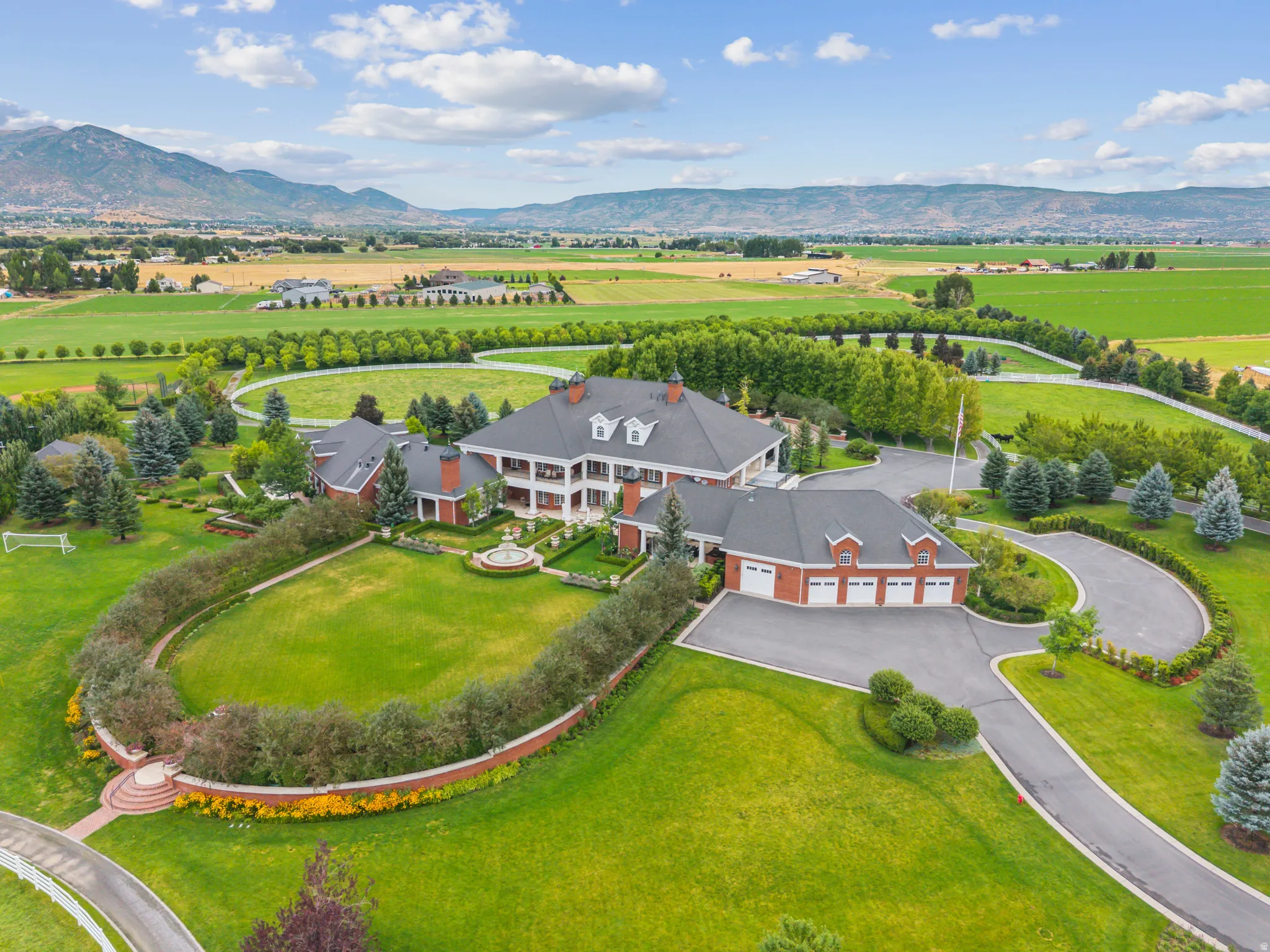 Expansive estate featuring a grand main residence with multiple dormers, a three-car garage, and extensive manicured grounds