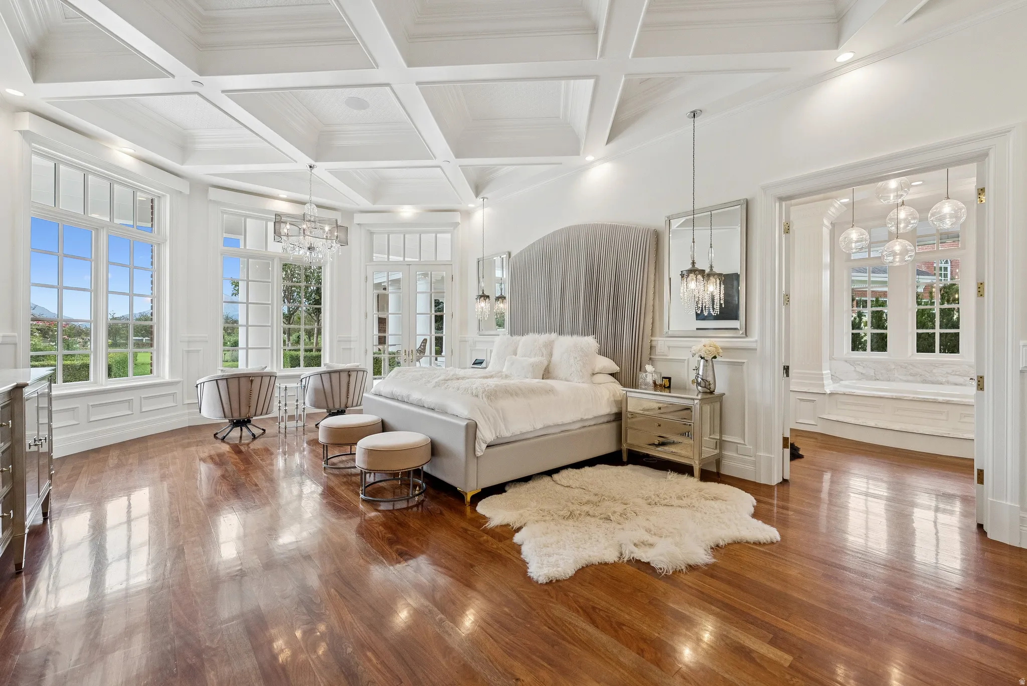 Hardwood flooring throughout a spacious room featuring a coffered ceiling and extensive wainscoting