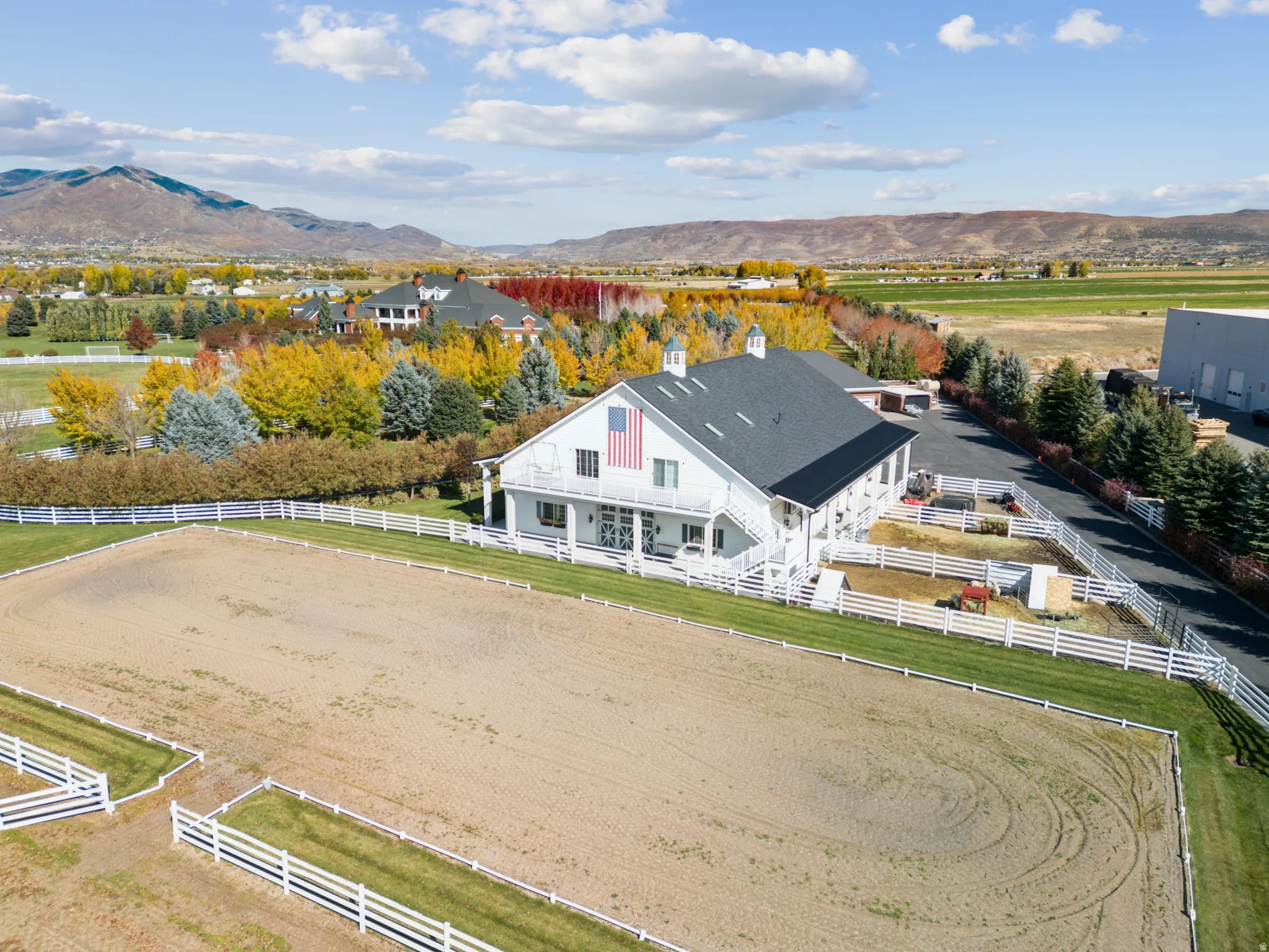 Large equestrian arena featuring sand footing and white fencing