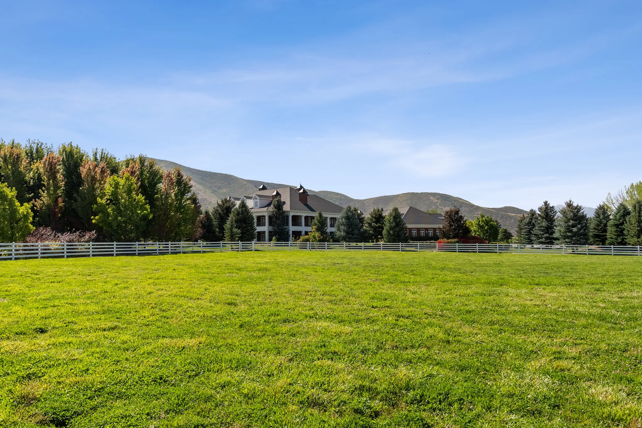 Expansive green lawn with a white picket fence bordering the property