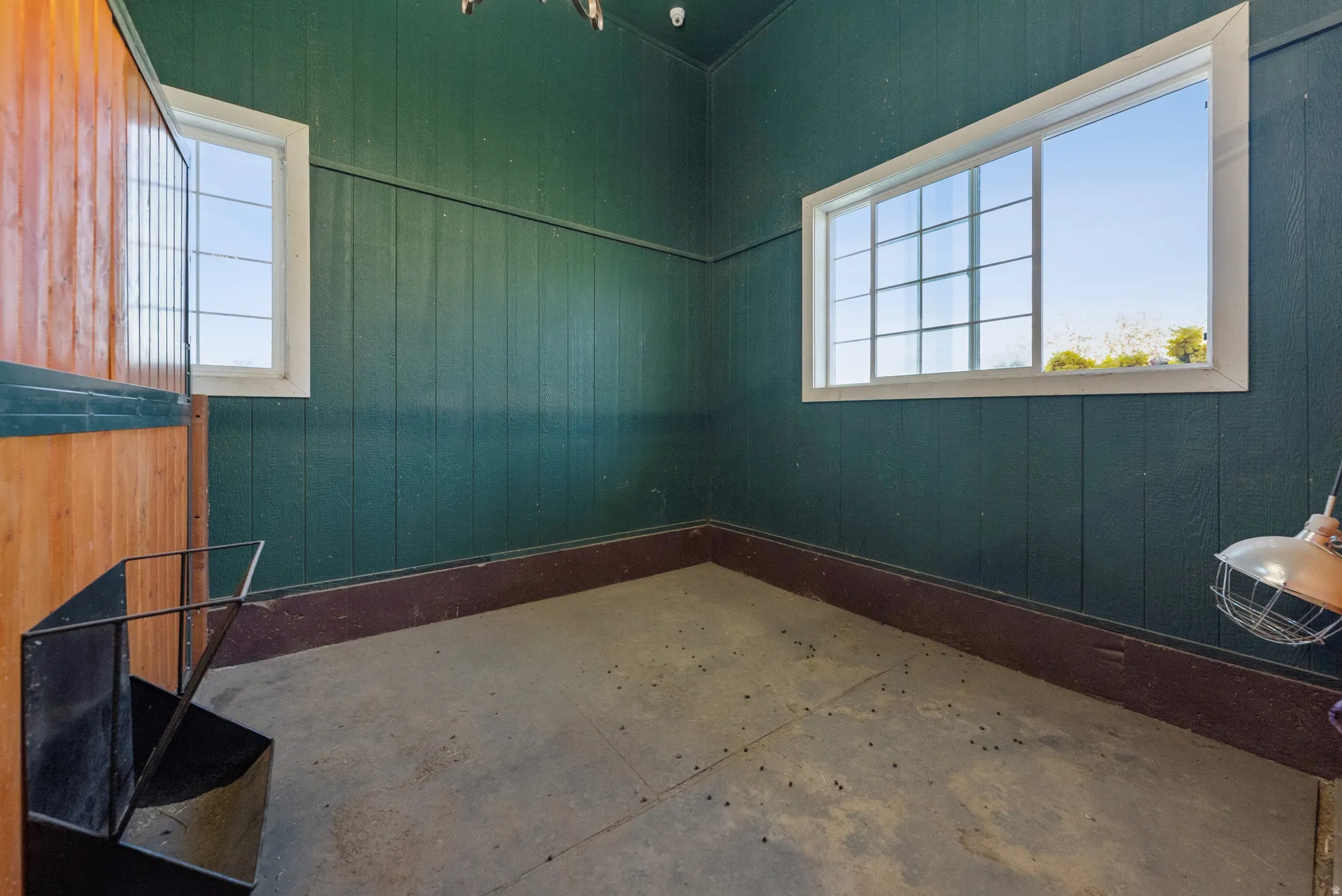 Interior space with dark green vertical paneling, concrete flooring, and a dark brown baseboard