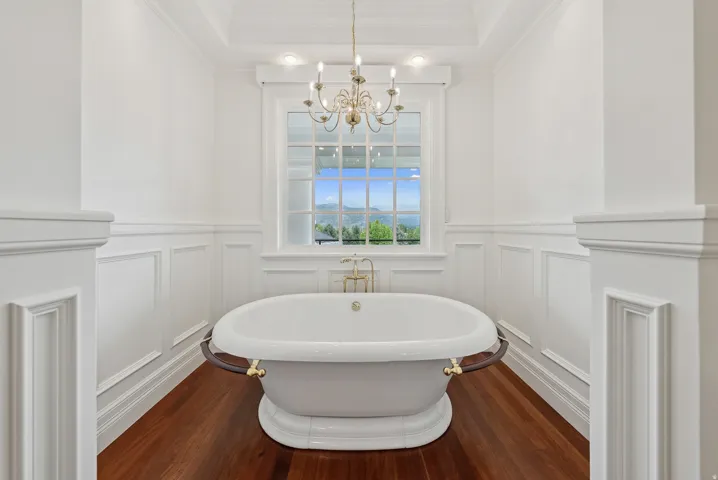 Freestanding soaking tub centered under a large window with mountain scenery