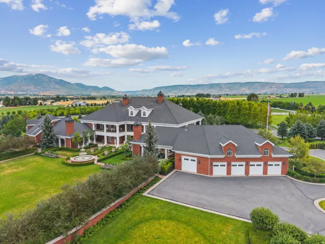Sprawling brick estate featuring a multi-car garage, extensive green lawns, and a central tiered fountain