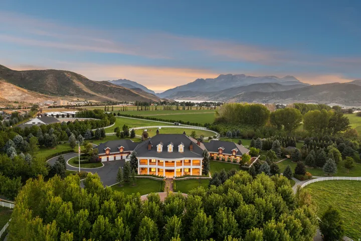 Expansive estate featuring a large main residence with a prominent front porch, multiple dormer windows, and attached garage structures