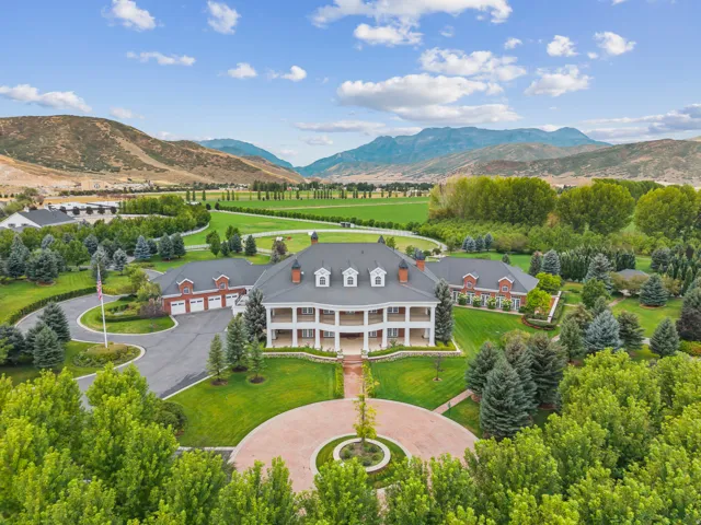 Colonial Revival estate with a grand circular driveway, extensive landscaping, mature trees, and mountain backdrop