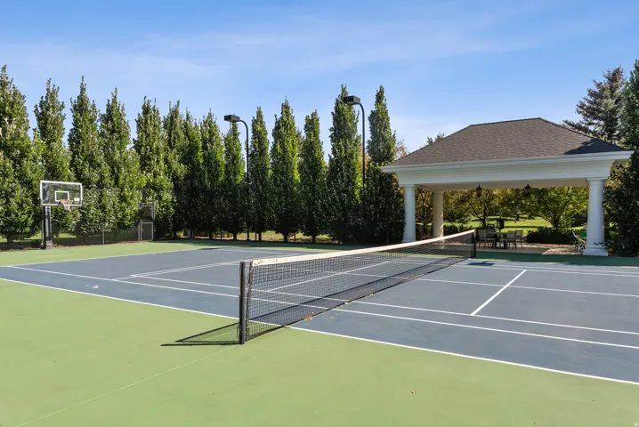 Multi-sport court featuring a tennis net, green and blue playing surfaces, and a basketball hoop