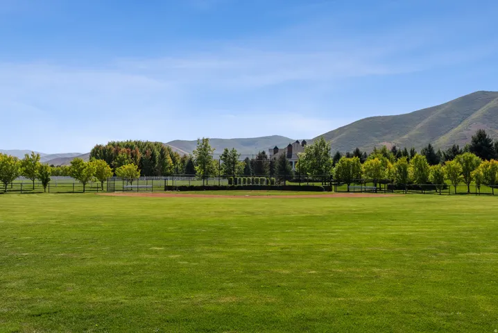 Expansive green lawn with a tree-lined perimeter and a mountain backdrop