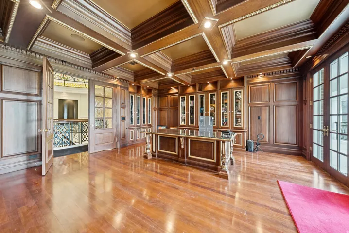 Wood-paneled room featuring a coffered ceiling with recessed lighting and gold-tone accents