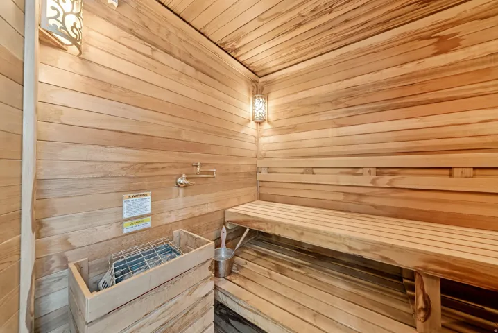 Dedicated sauna room featuring extensive wood paneling, built-in benches, and an integrated sauna heater