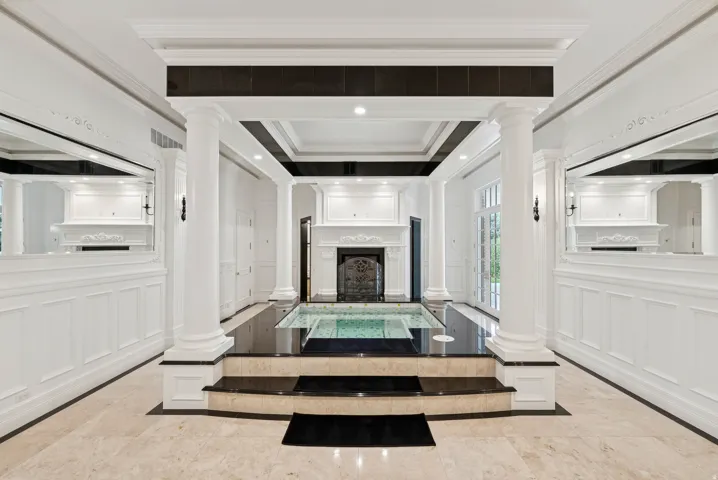 Indoor pool featuring a black tile surround, decorative iron grate, and recessed lighting