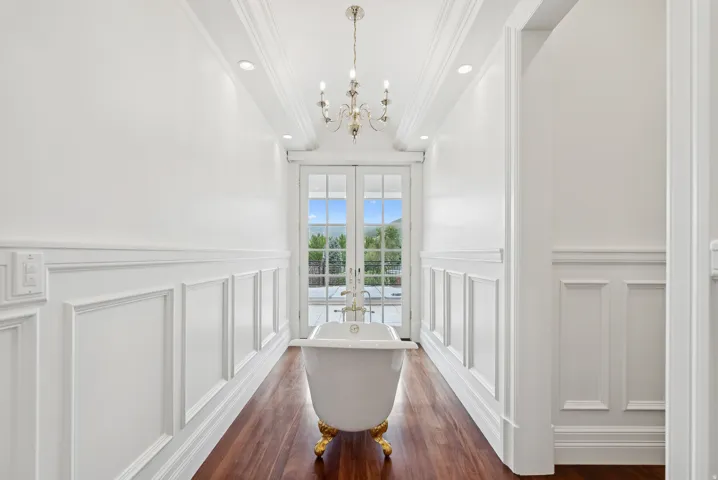 Clawfoot tub with gold-tone feet and fixtures, set on wood-finish flooring
