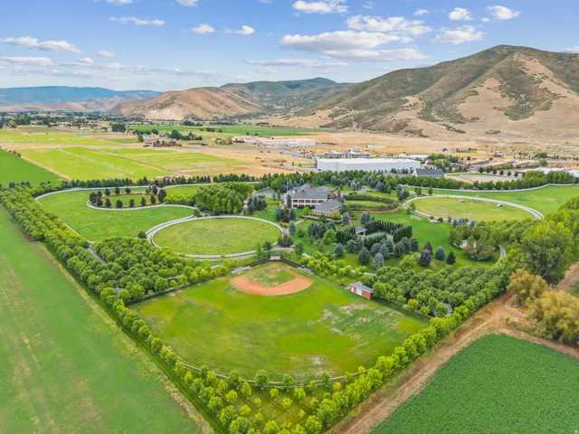 Expansive agricultural property featuring a baseball diamond, multiple manicured fields, mature tree lines, and a large central residence with surrounding landscaping