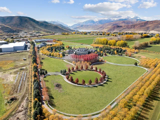 Extensive property featuring a large estate house, multiple outbuildings, vast green lawns, mature trees, and a mountain backdrop
