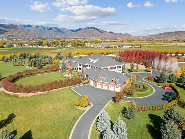 Expansive property featuring a multi-structure residence with red brick and white siding accents, a circular driveway, and a three-car garage