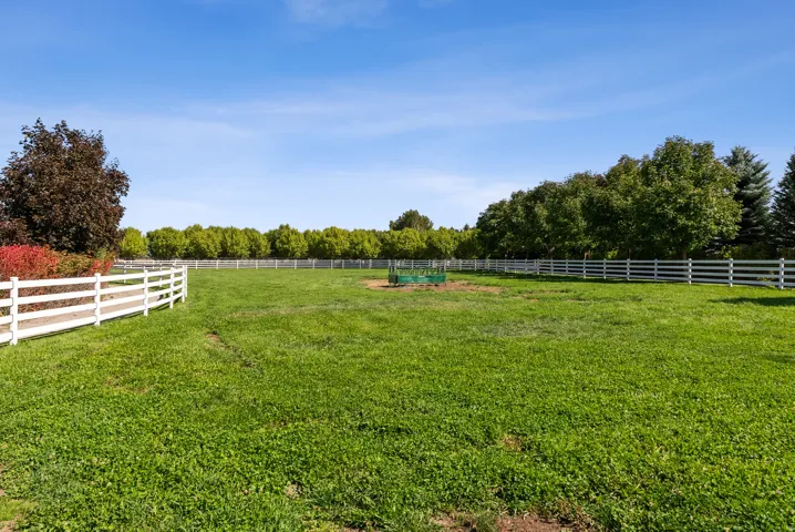 Expansive green lawn enclosed by white fencing