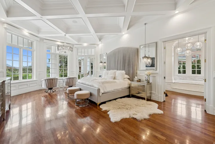 Hardwood flooring throughout a spacious room featuring a coffered ceiling and extensive wainscoting