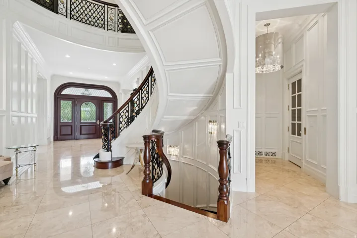 Grand foyer featuring a curved staircase with dark wood newel posts and an ornate black wrought-iron railing