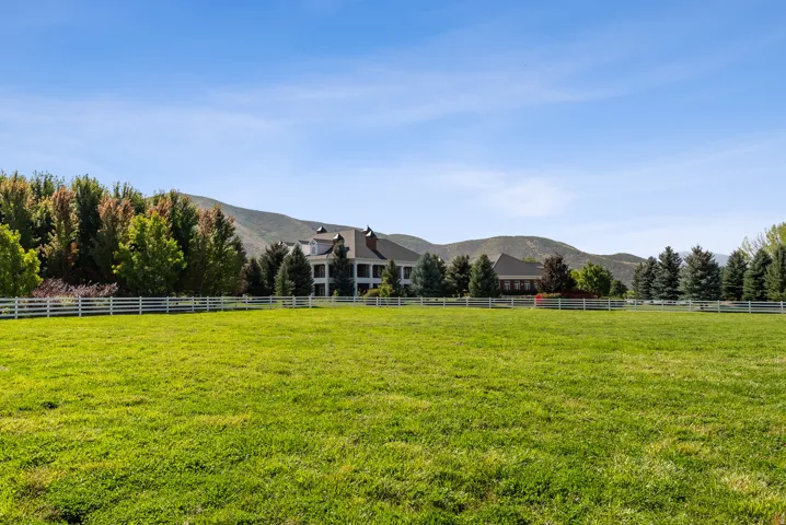 Expansive green lawn with a white picket fence bordering the property