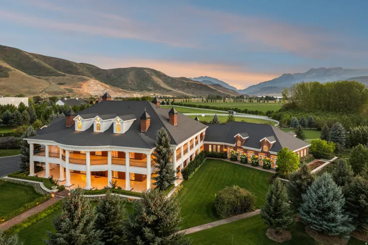 Expansive estate featuring a multi-story, white-columned facade and a distinct brick wing