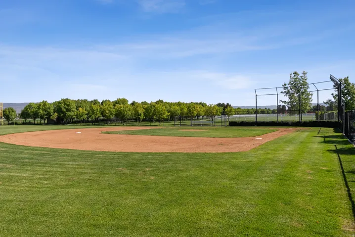 Baseball field featuring a manicured outfield, dirt infield, and surrounding chain-link fencing