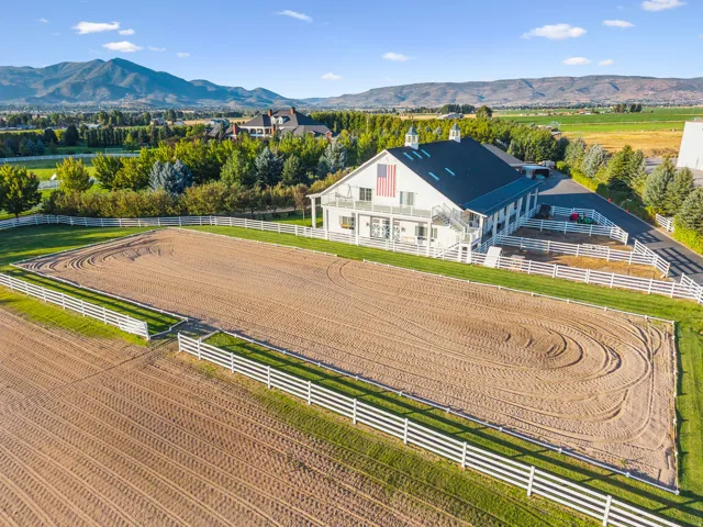 Expansive outdoor arena featuring a sand surface and white perimeter fencing