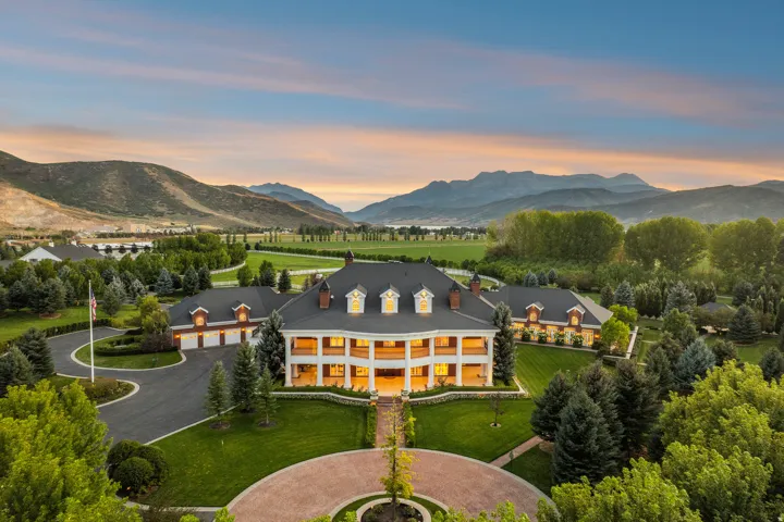 Expansive estate featuring a grand two-story colonial-style residence with a wide front porch and dormer windows