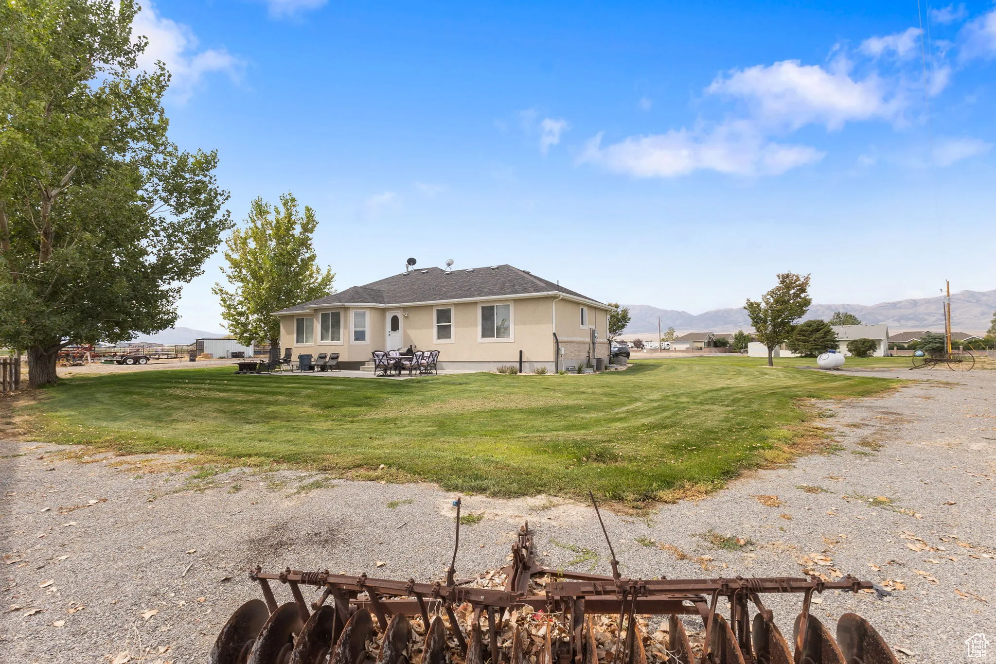 Rear view of house featuring a mountain view, a patio area, a lawn, and stucco siding