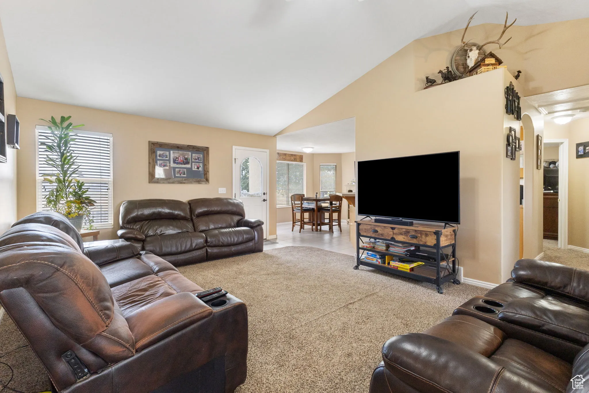 Carpeted living area with high vaulted ceiling and baseboards