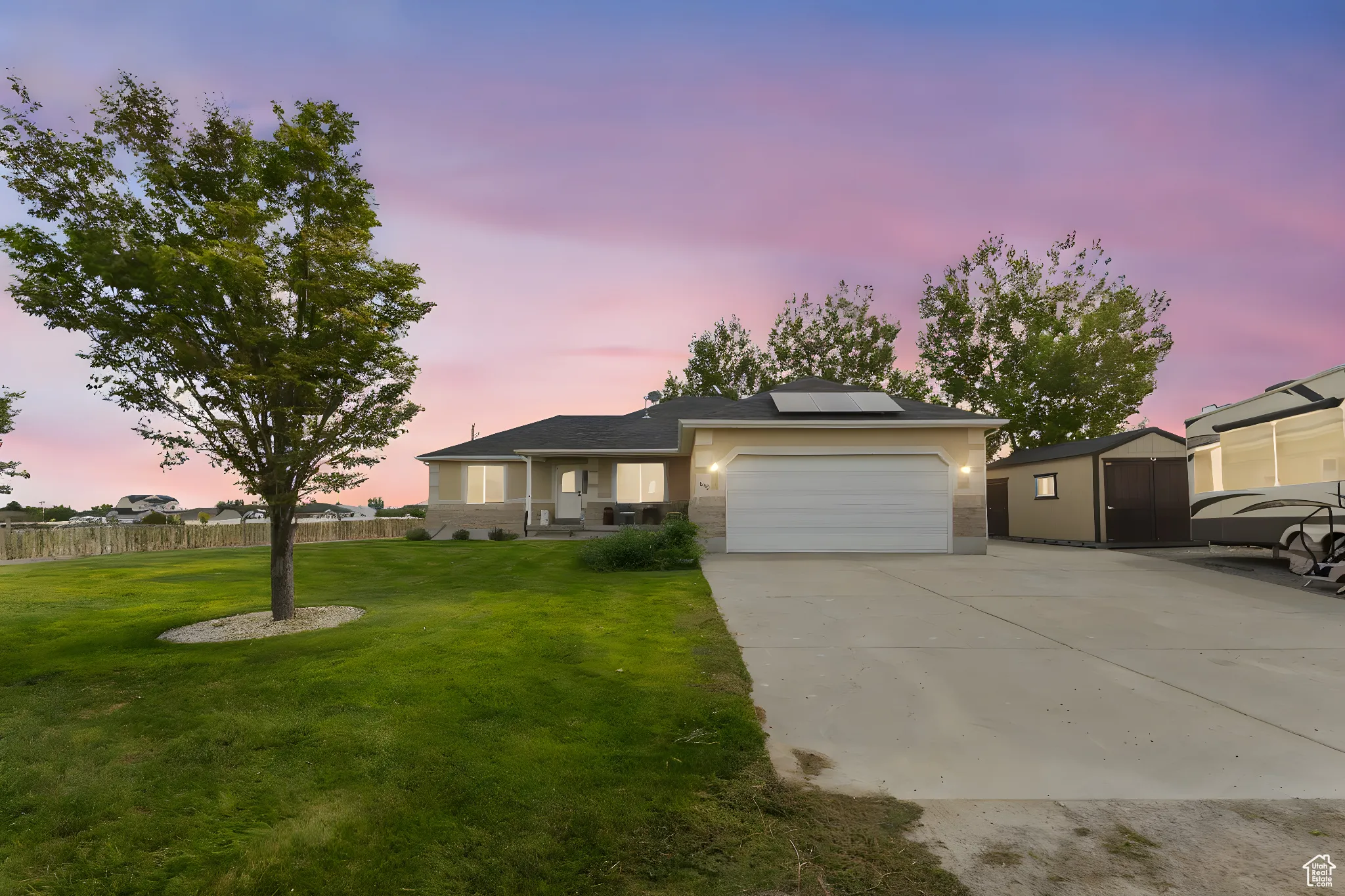 Ranch-style house featuring solar panels, concrete driveway, a garage, brick siding, and stucco siding