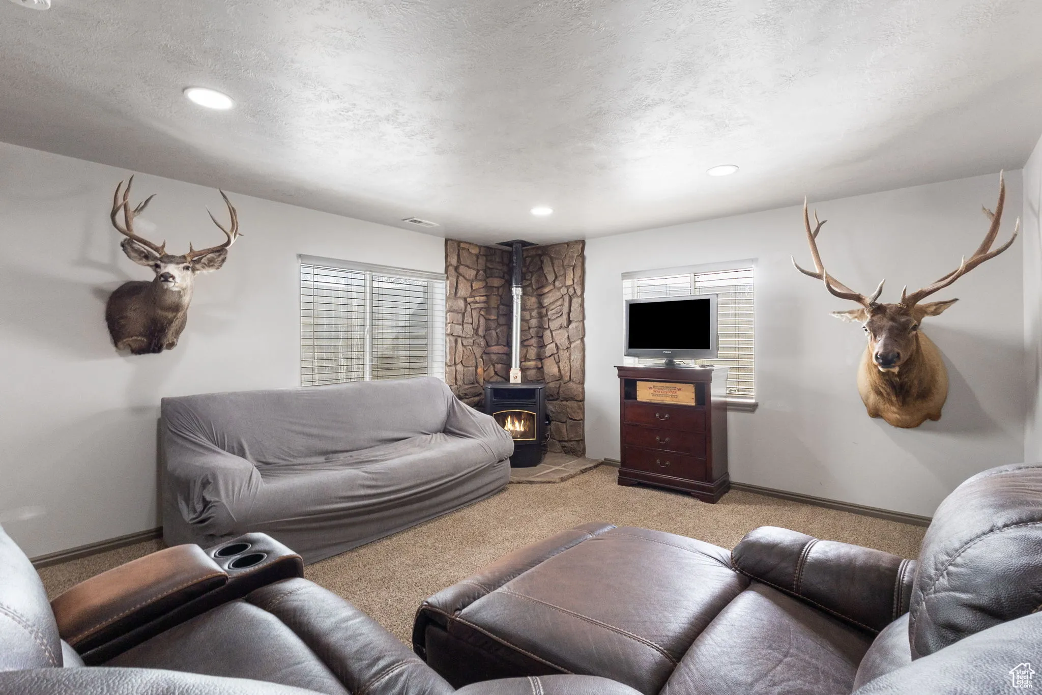 Carpeted living room featuring a wood stove, a textured ceiling, and recessed lighting