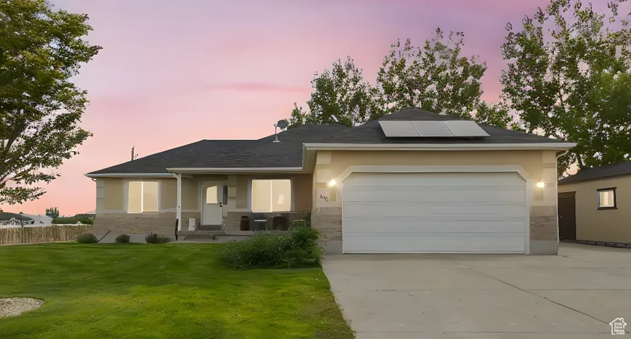 View of front of home featuring roof mounted solar panels, concrete driveway, and stucco siding