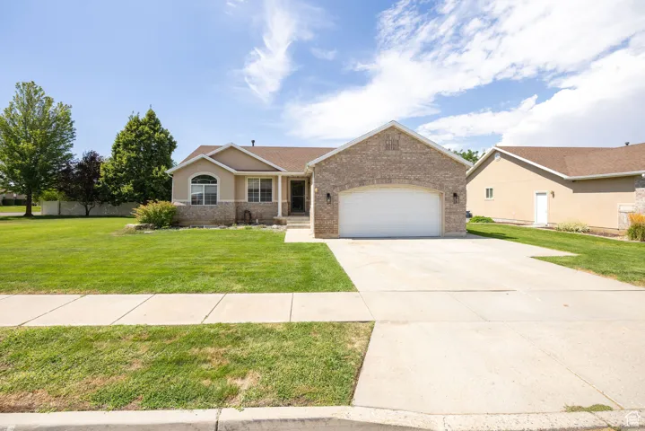 Ranch-style home featuring concrete driveway, a front lawn, a garage, and brick siding