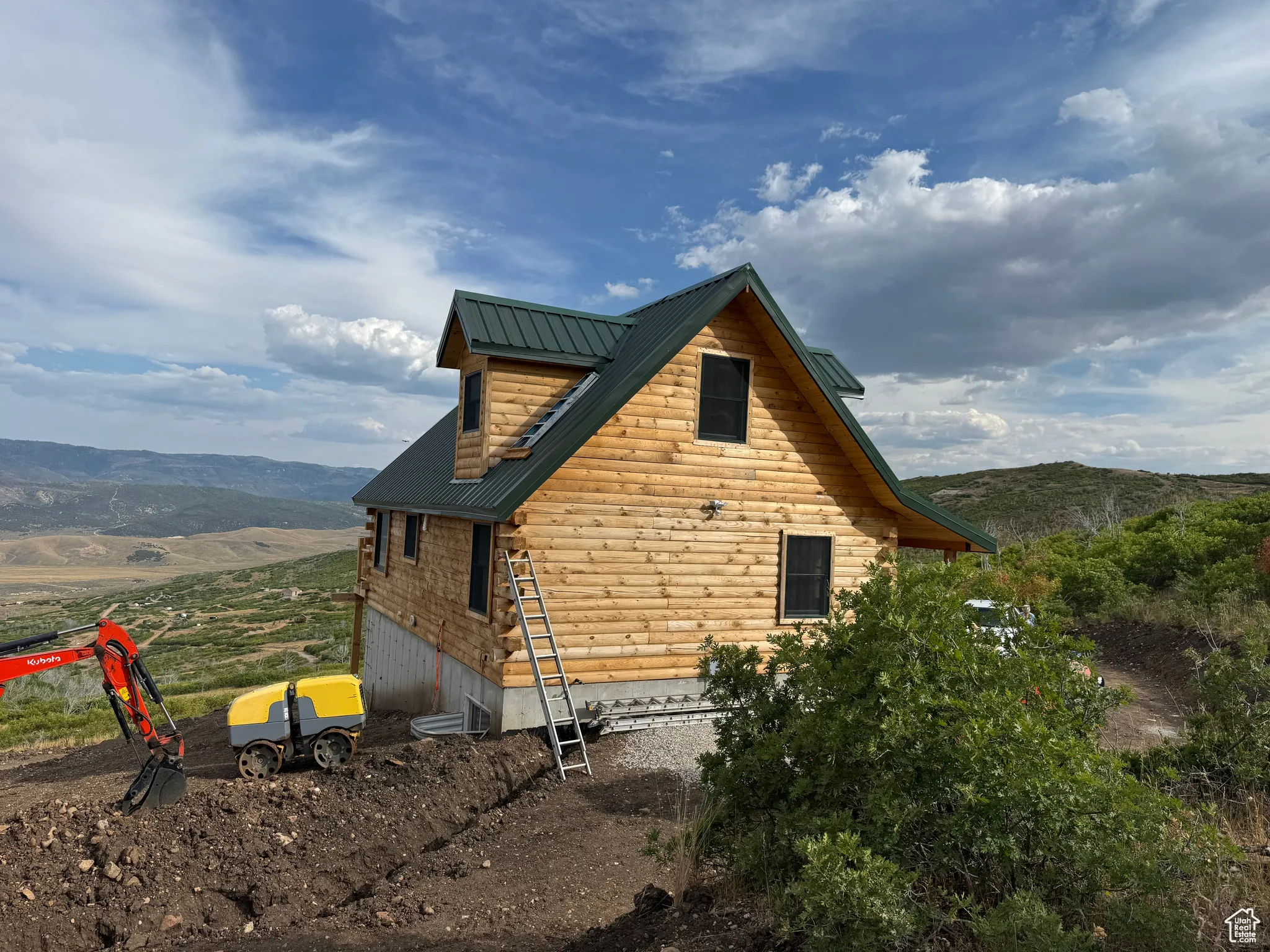 View of property exterior with a mountain view, log exterior, and a metal roof