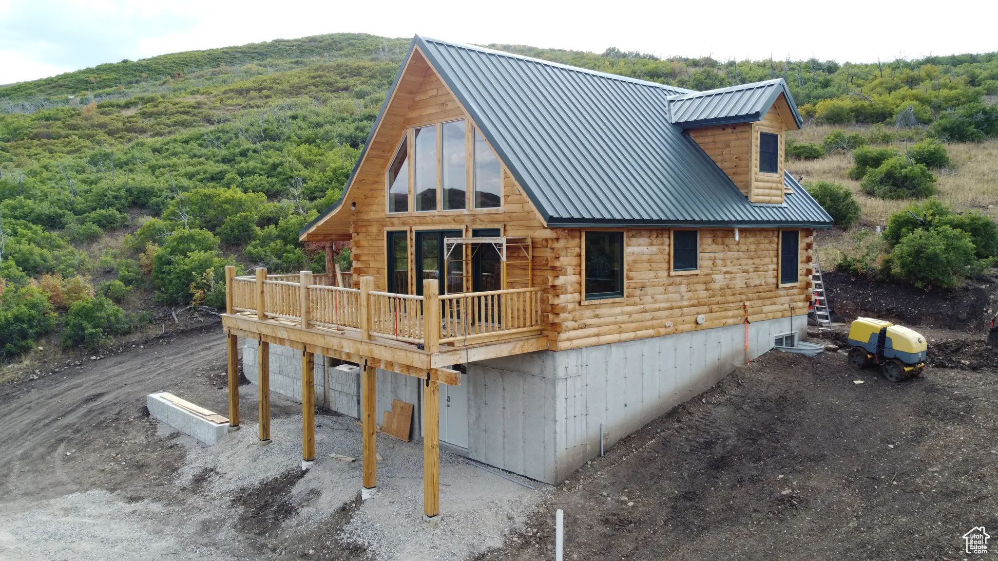 Rear view of house featuring log exterior, a deck, a metal roof, and a wooded view
