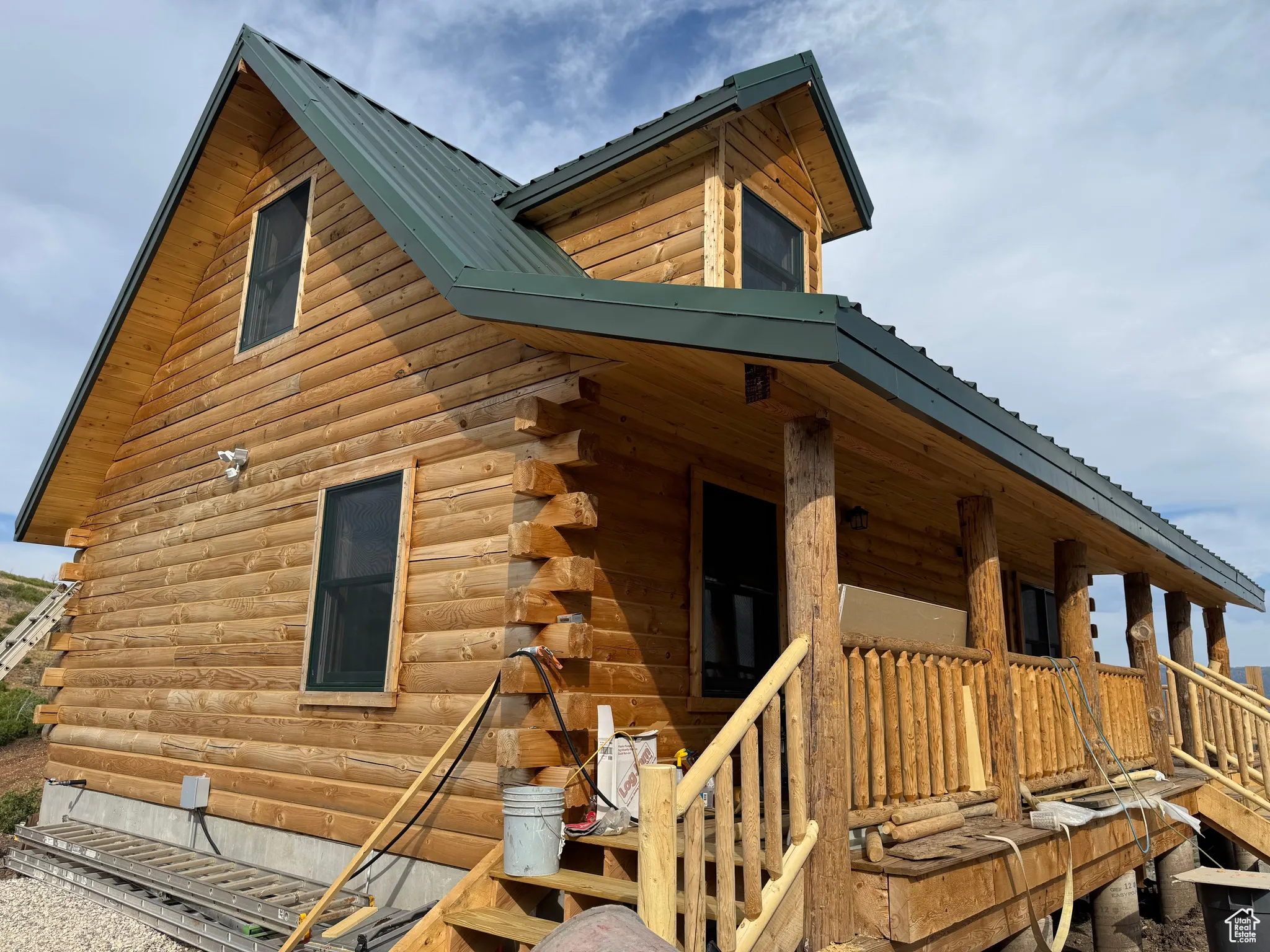View of side of property with a metal roof, log siding, a porch, and stairs