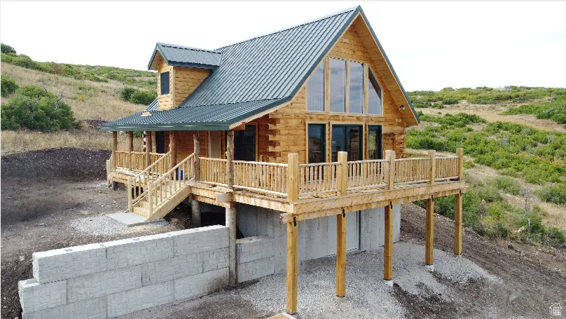 View of property with log exterior, a metal roof, and a porch