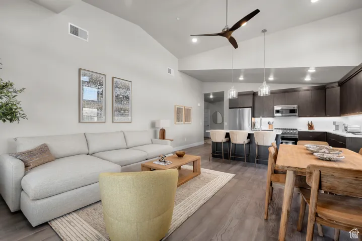Living area with light wood finished floors, ceiling fan, high vaulted ceiling, and recessed lighting