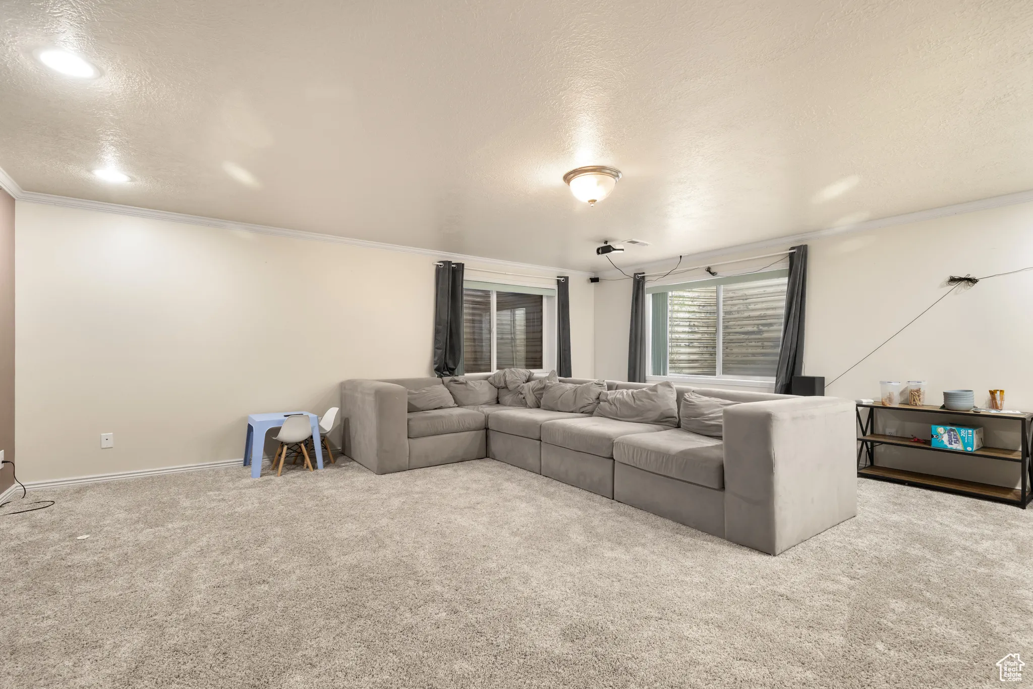 Carpeted living room featuring a textured ceiling and ornamental molding