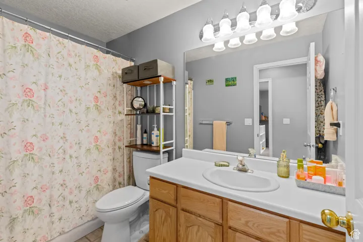 Full bathroom with vanity, a textured ceiling, and light tile patterned flooring